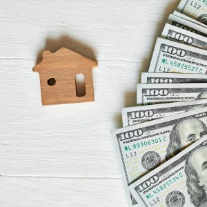 Small wooden house and hundred dollar on white background, concept of real estate, growth of mortgage credit, Property investment and house mortgage financial concept.